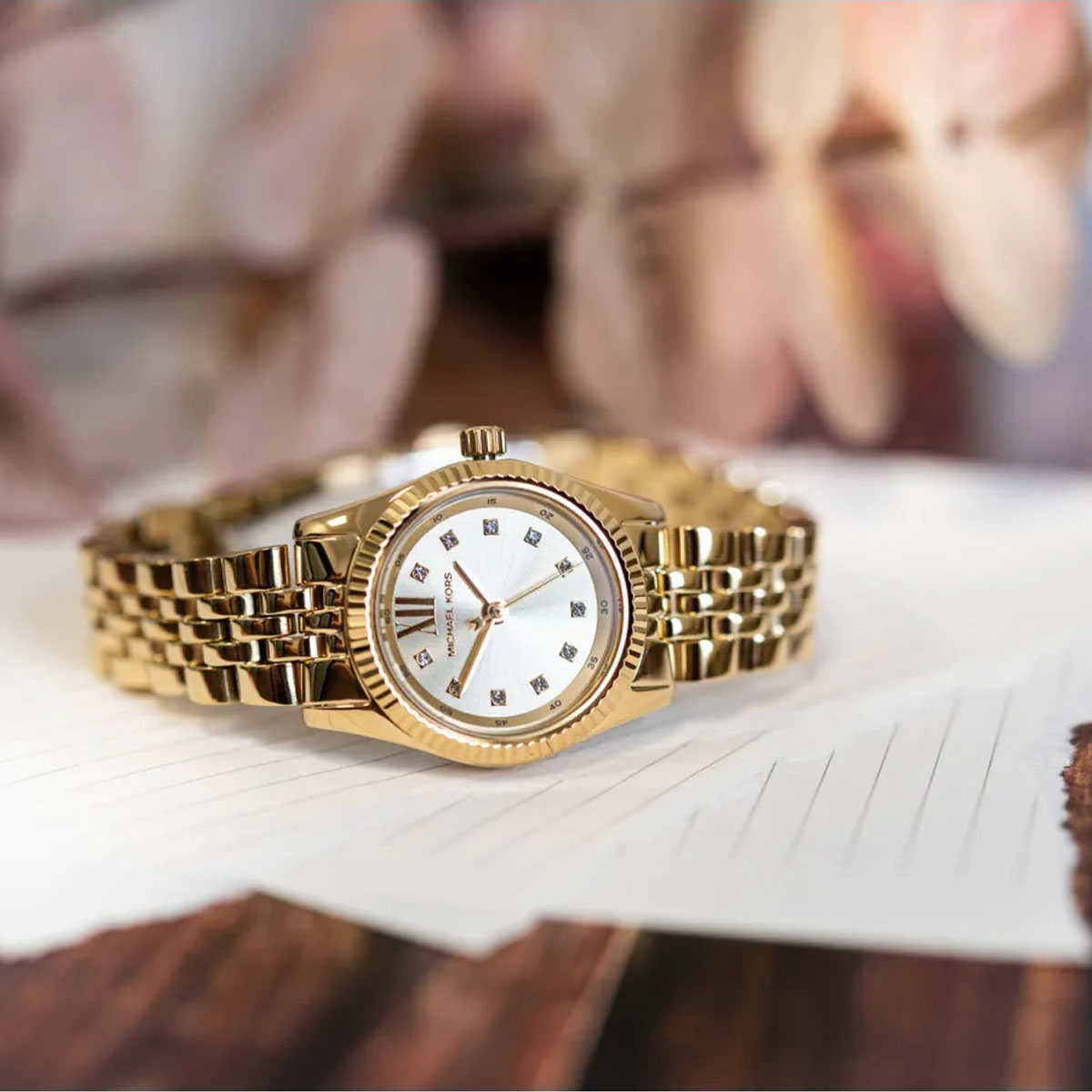 Złoty damski zegarek Michael Kors na drewnianym blacie