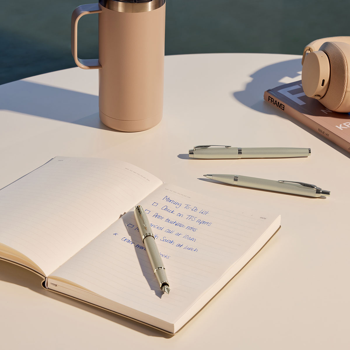 Zestaw Parker IM Monochrome Champagne pióro i długopis ułożone na notesie na białym stole