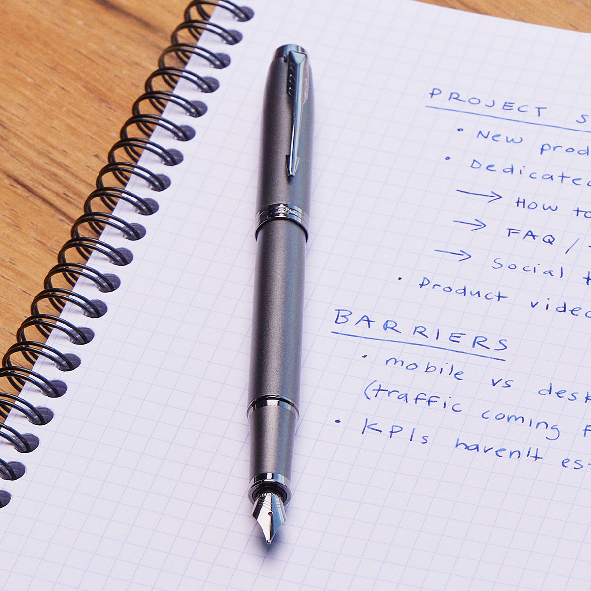 Pióro wieczne Parker IM Monochrome Bronze na biurku obok notatek i szklanki wody