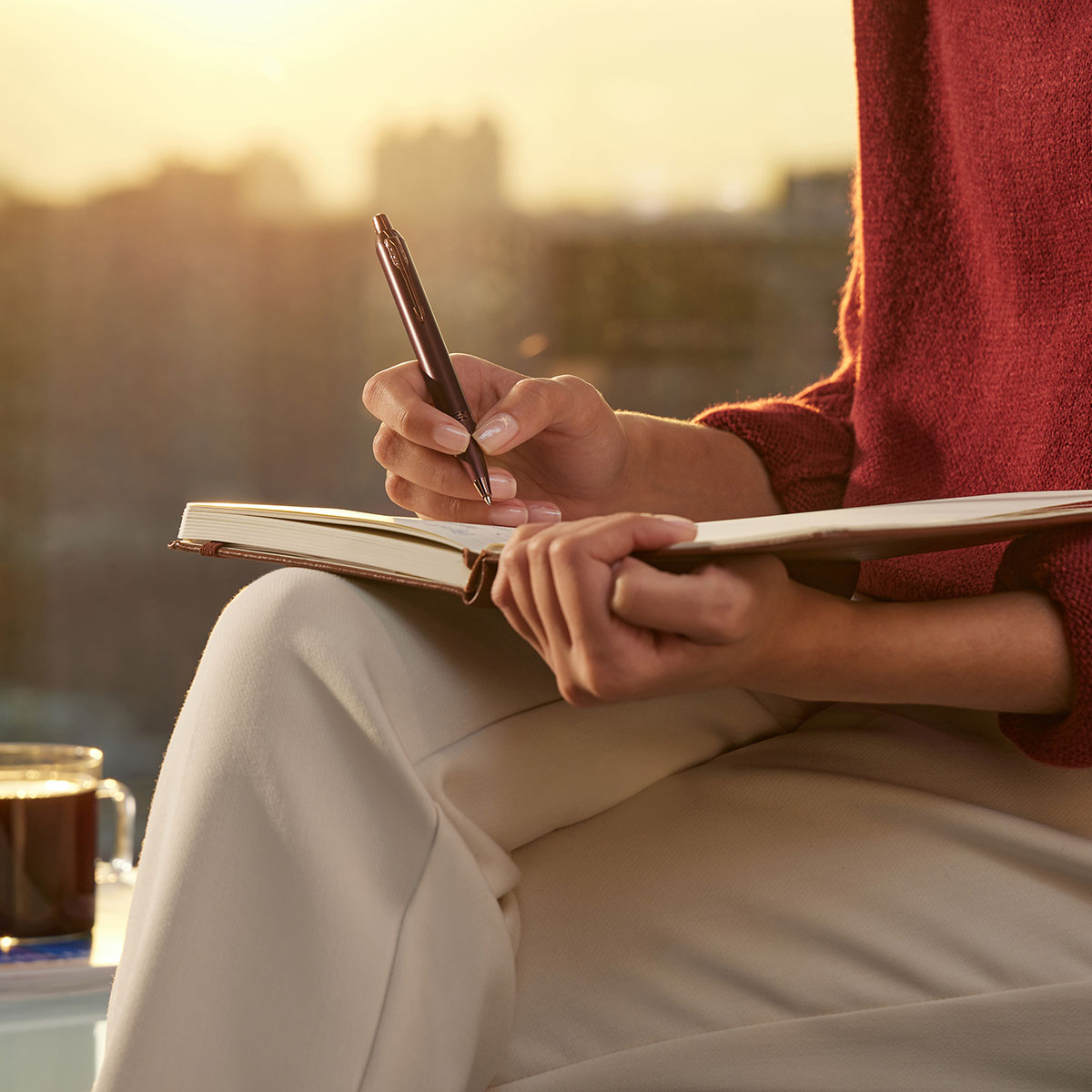 Długopis Parker IM Monochrome Burgundy CT trzymany w dłoni, notatki przy zachodzie słońca