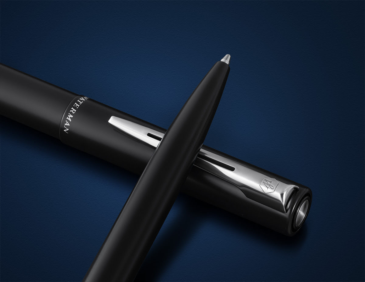 Długopis Waterman Allure czarny matowy CT uchwycony na ciemnoniebieskim tle ze skuwką obok korpusu.