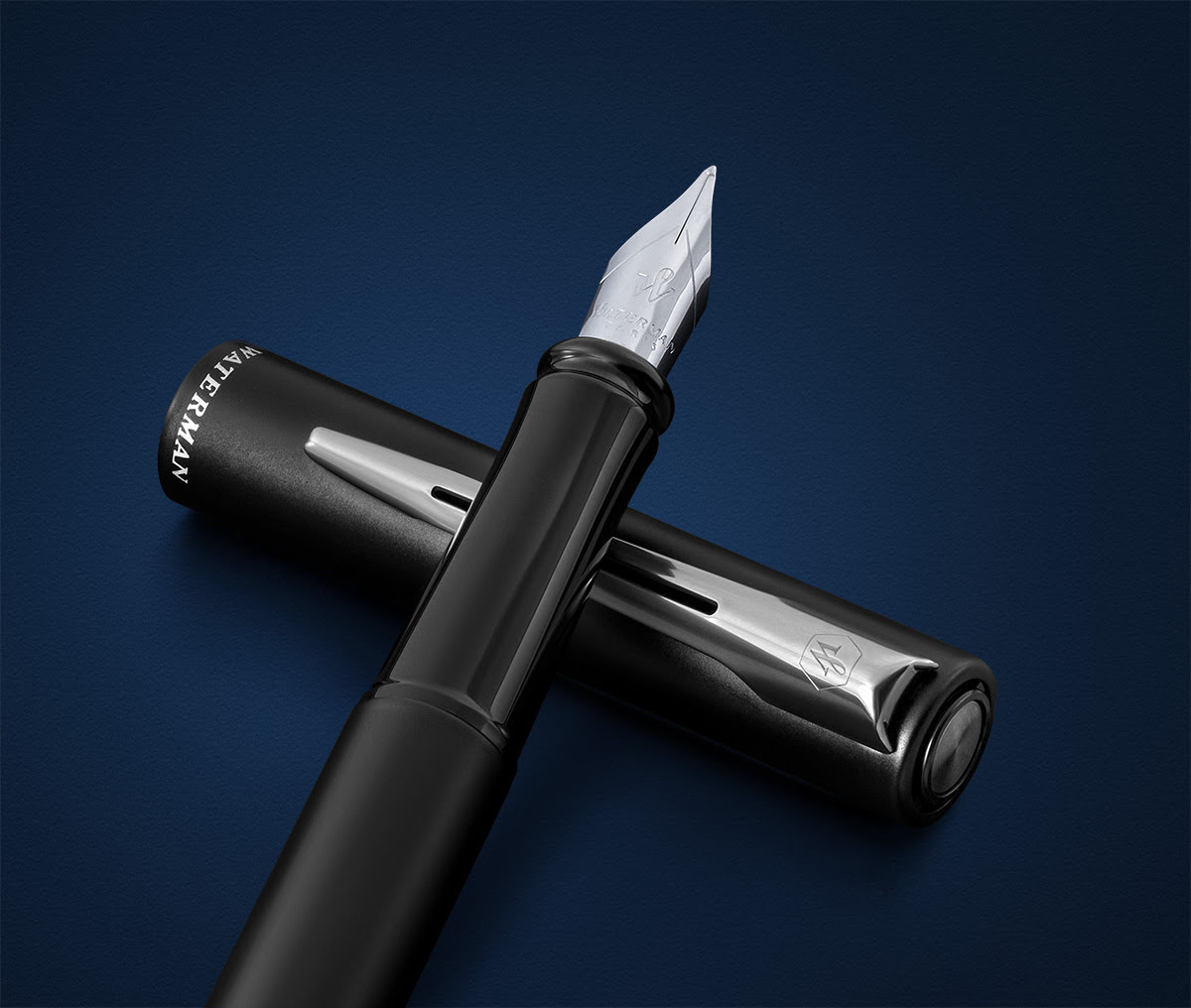 Pióro wieczne Waterman Allure czarne matowe CT uchwycone w zbliżeniu na ciemnoniebieskim tle ze skuwką obok.