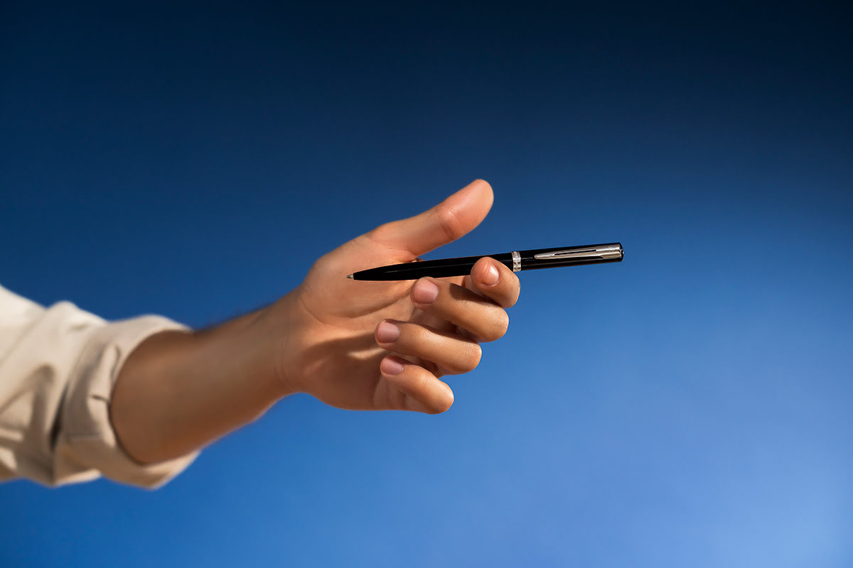 Długopis Waterman Allure Impression czarny CT trzymany w dłoni mężczyzny na granatowym tle