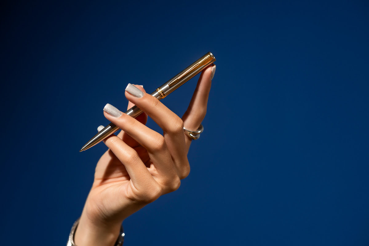 Długopis Waterman Allure Impression stalowy GT prezentowany w dłoni na gładkim granatowym tle, ujęcie detalu