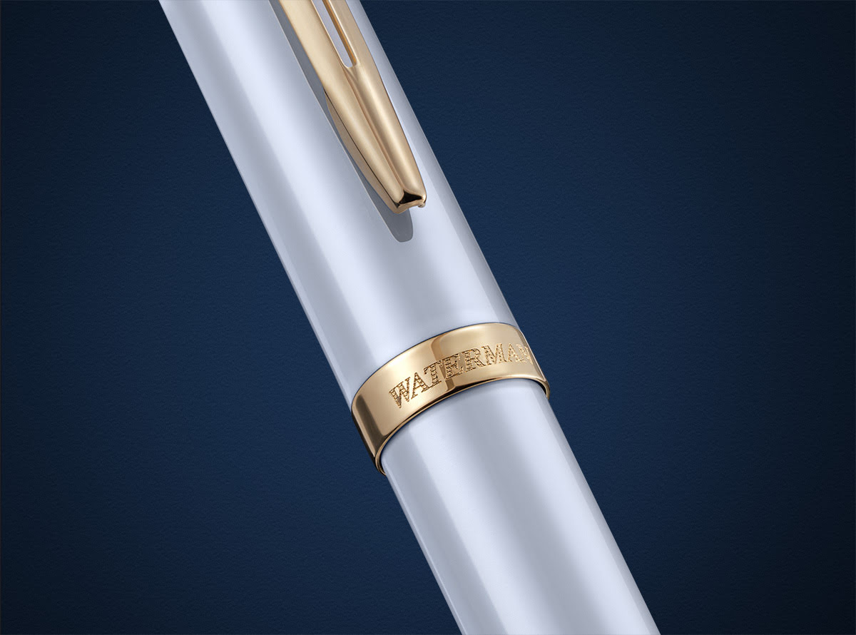 Pióro Waterman Allure Impression białe GT w zbliżeniu na złoty klips i grawerowany pierścień na tle granatu