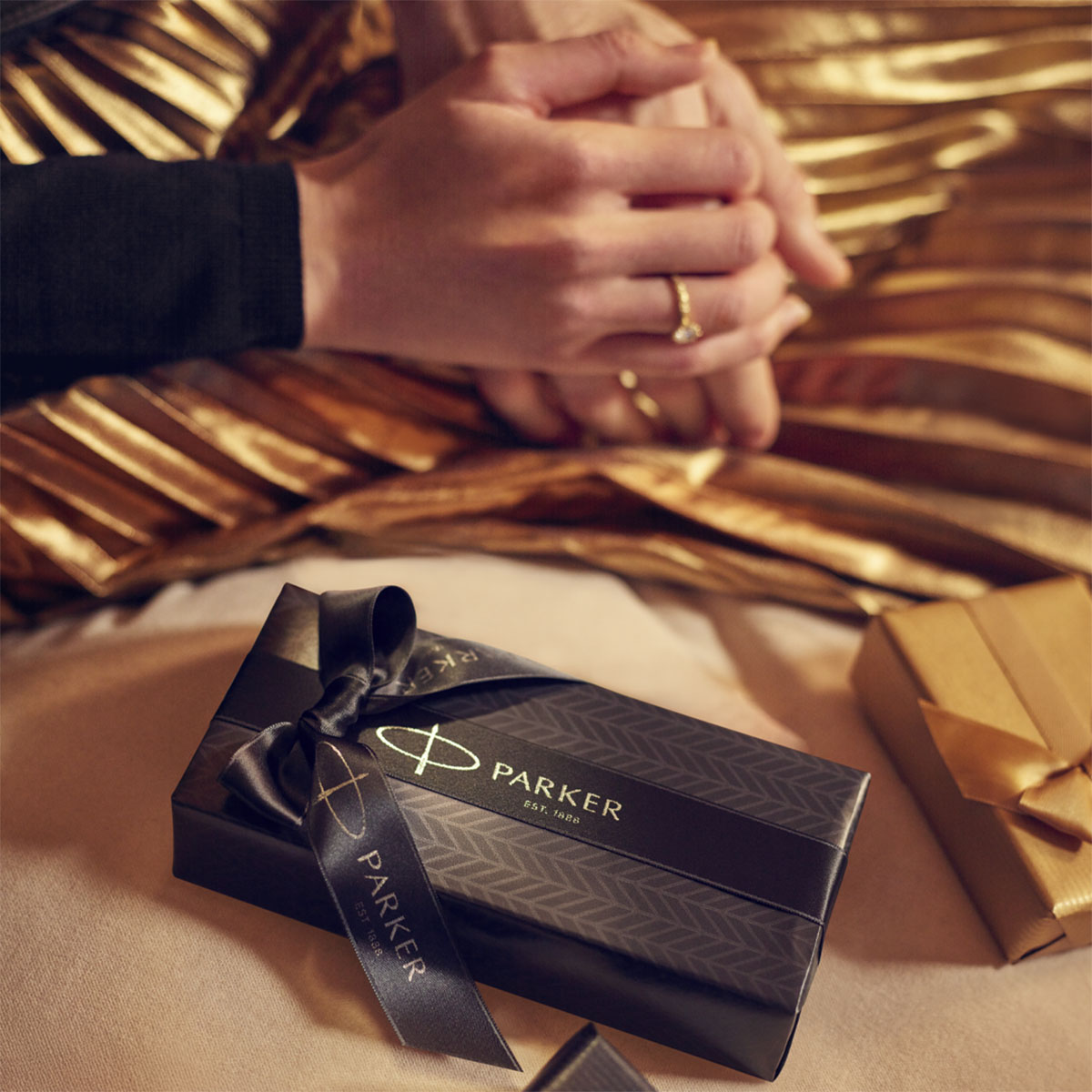 Pudełko prezentowe Parker przewiązane czarną wstążką w eleganckiej aranżacji świątecznej z motywem złota