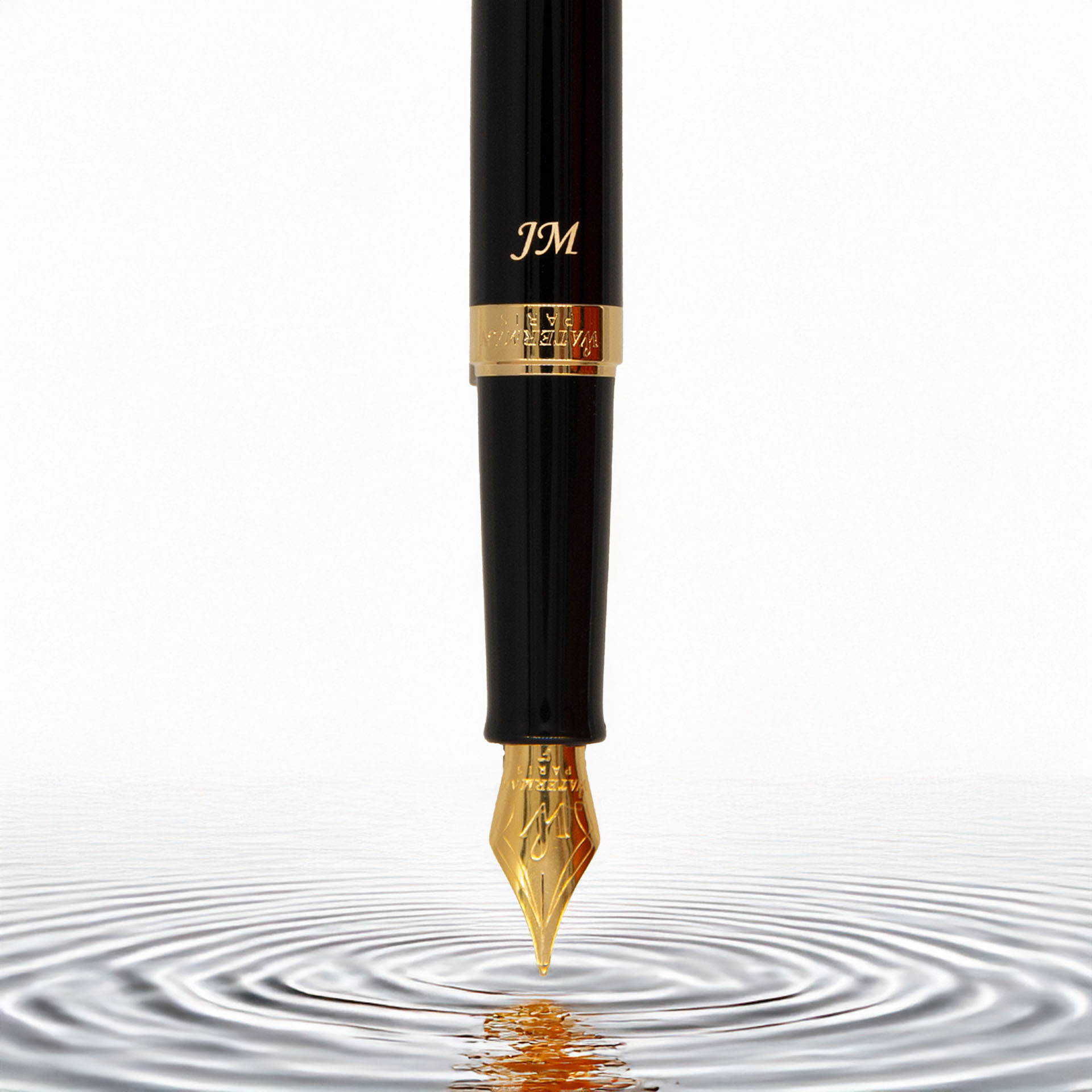 Złote pióro wieczne dotykające tafli wody, tworzące delikatne fale