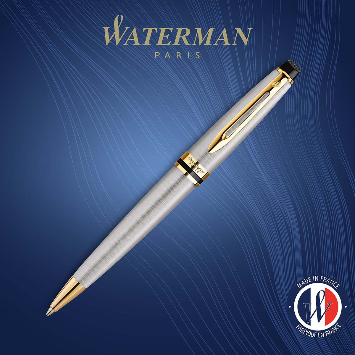 długopis Waterman Expert stalowy GT ze szczotkowanej stali i złotymi detalami na tle z logo Waterman Paris