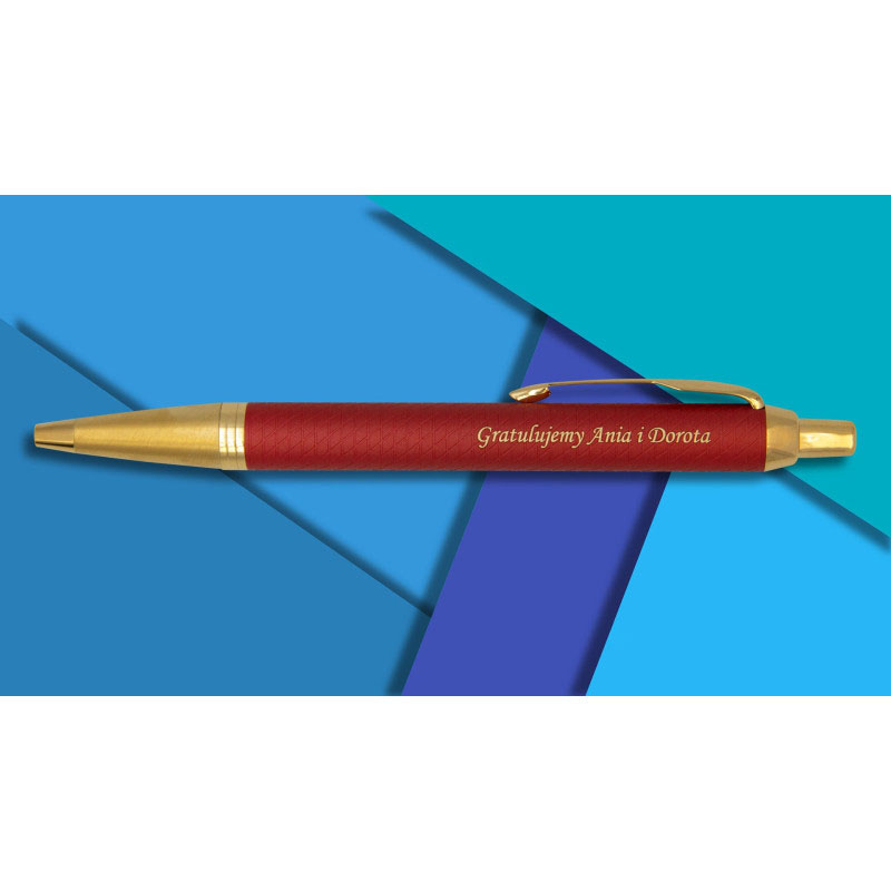 Czerwony długopis Parker IM Premium GT z grawerem „Gratulujemy Ania i Dorota” na tle geometrycznym w odcieniach niebieskiego.