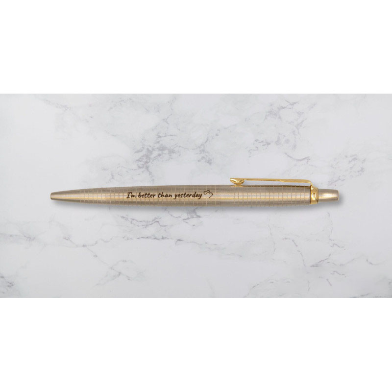 Długopis Parker Jotter w wersji złotej z grawerem „I'm better than yesterday” na marmurowym tle.