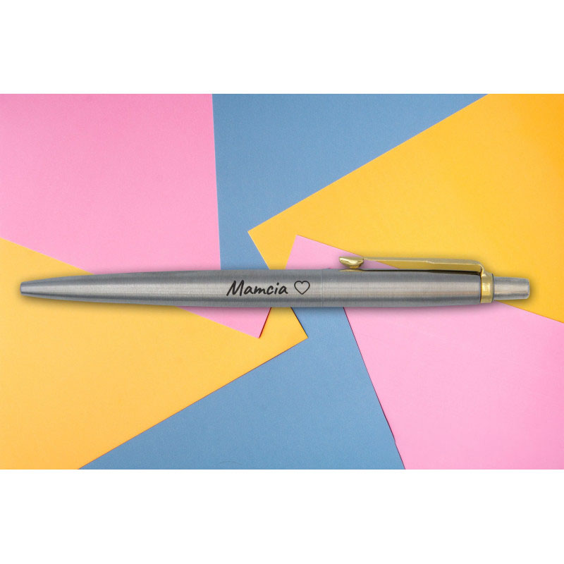 Długopis Parker Jotter stalowy matowy z grawerem „Mamcia ♥” na tle kolorowych arkuszy papieru.