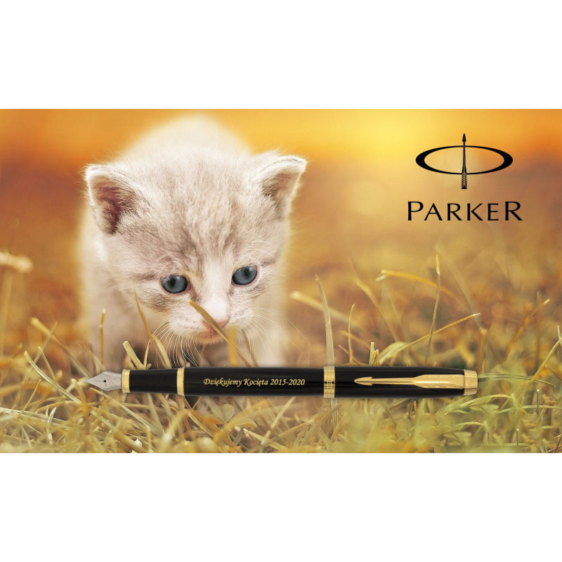 Czarne pióro wieczne Parker IM GT z pozłacanymi wykończeniami i grawerem „Dziękujemy Kocięta 2015-2020”, umieszczone na tle fotografii z małym, jasnoszarym kotkiem o niebieskich oczach wśród traw. W prawym górnym rogu widoczne jest logo marki Parker.