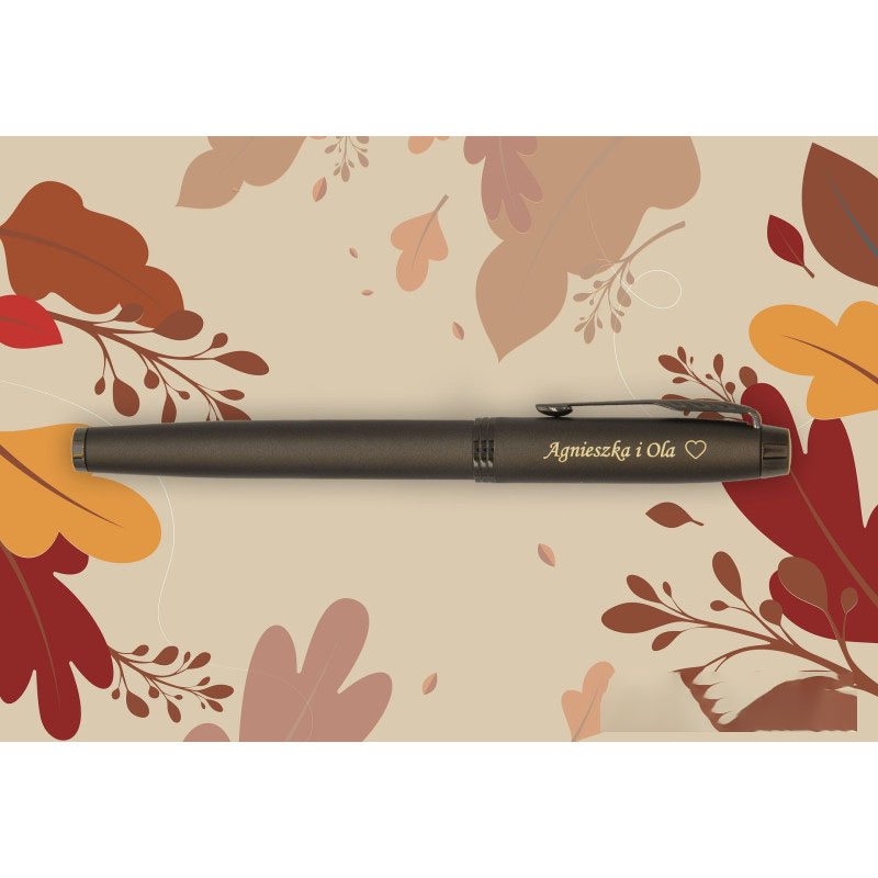 Pióro wieczne Parker IM Professionals Monochrome Bronze w jednolitej, matowej, brązowo-miedzianej kolorystyce z czarnym klipsem w kształcie strzały. Na korpusie, tuż przy skuwce, widoczny jest grawer w złotym kolorze z napisem „Agnieszka i Ola” oraz symbo