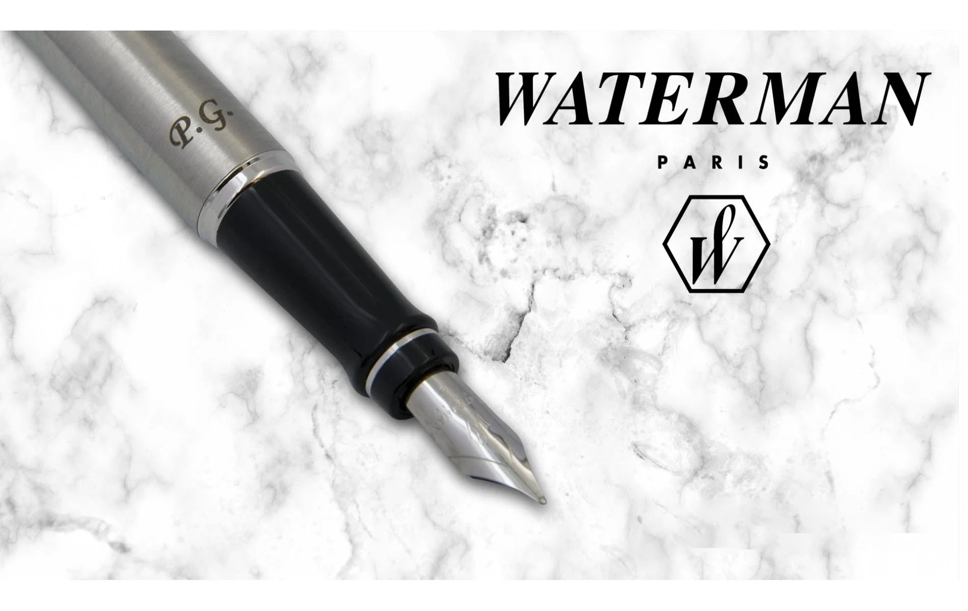 Pióro wieczne Waterman Expert stalowe CT [S0952040] z inicjałami „P.G.” wygrawerowanymi na korpusie, zaprezentowane na tle białego marmuru obok logo marki Waterman Paris.