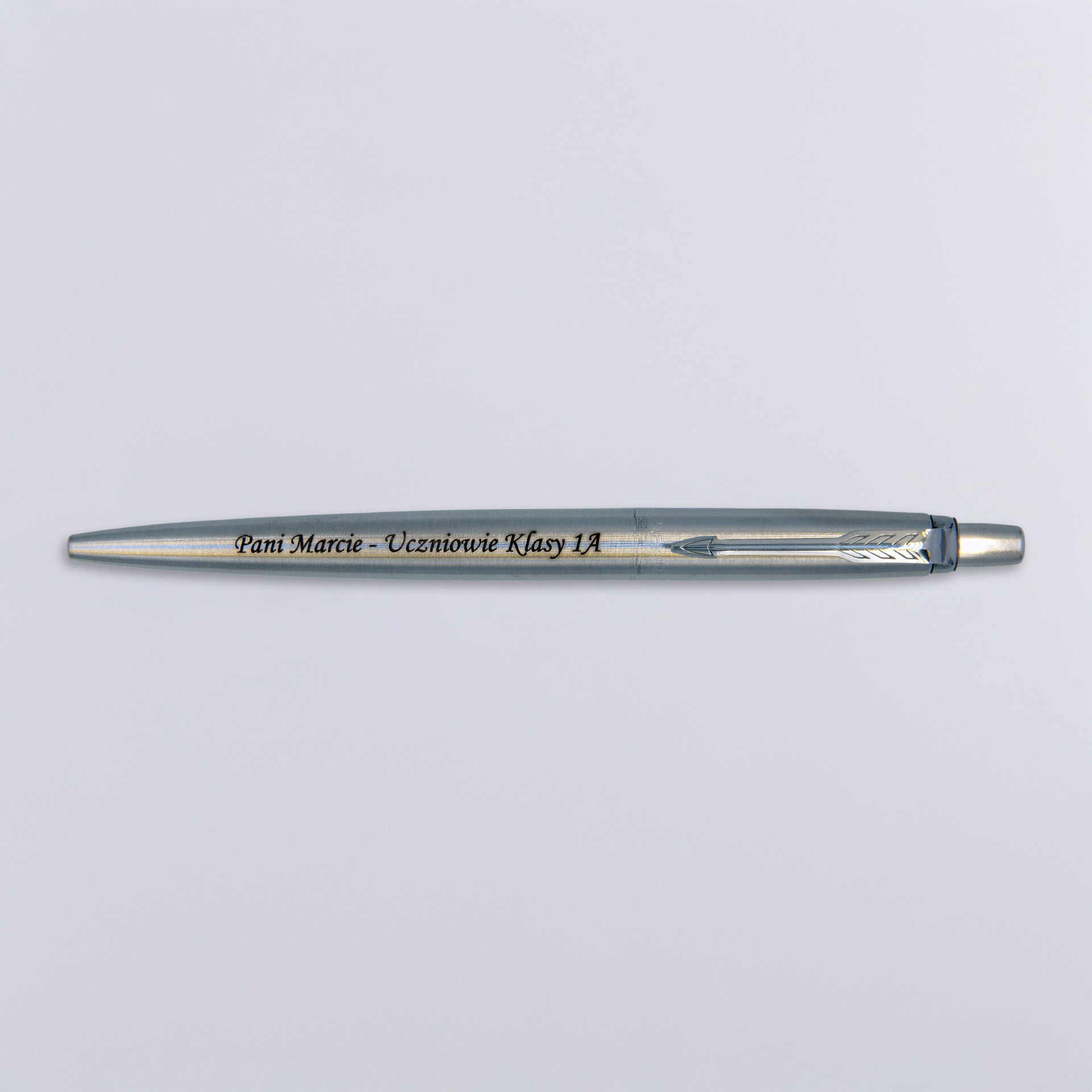Długopis Parker Jotter Stalowy Matowy CT (1953170) z grawerem „Pani Marcie – Uczniowie Klasy 1A”, ułożony na jasnym tle, w minimalistycznym ujęciu podkreślającym elegancję i symboliczny charakter prezentu.