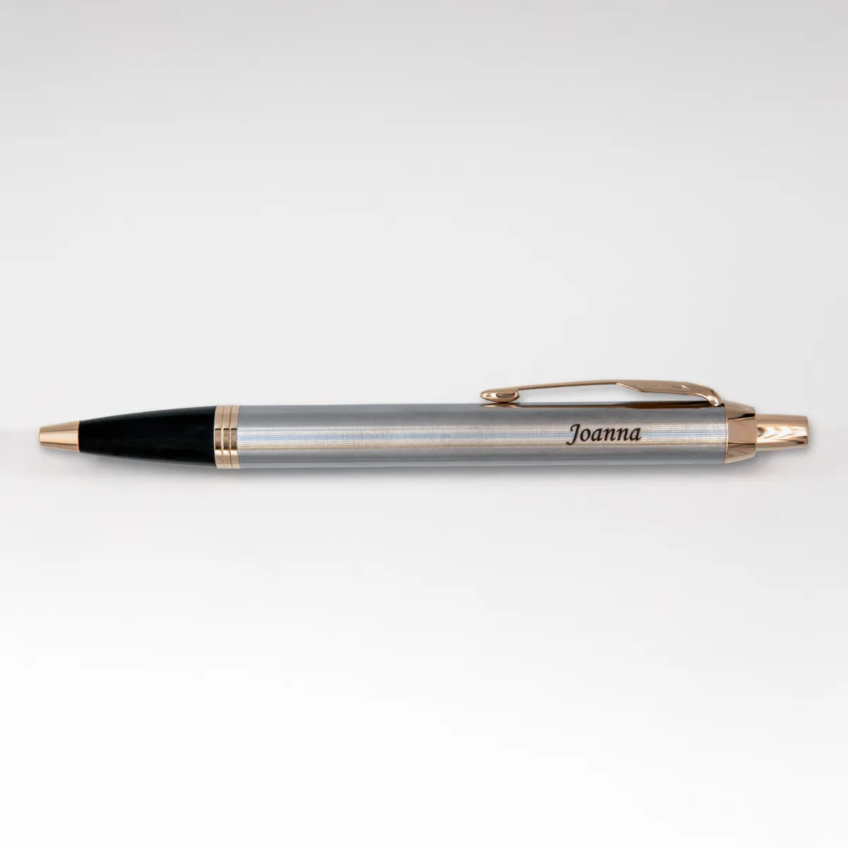 Długopis Parker IM Brushed Metal GT (1931670) z grawerem „Joanna”, sfotografowany na jasnym tle. Delikatne światło podkreśla połysk złotych detali i elegancki charakter klasycznego wzornictwa.