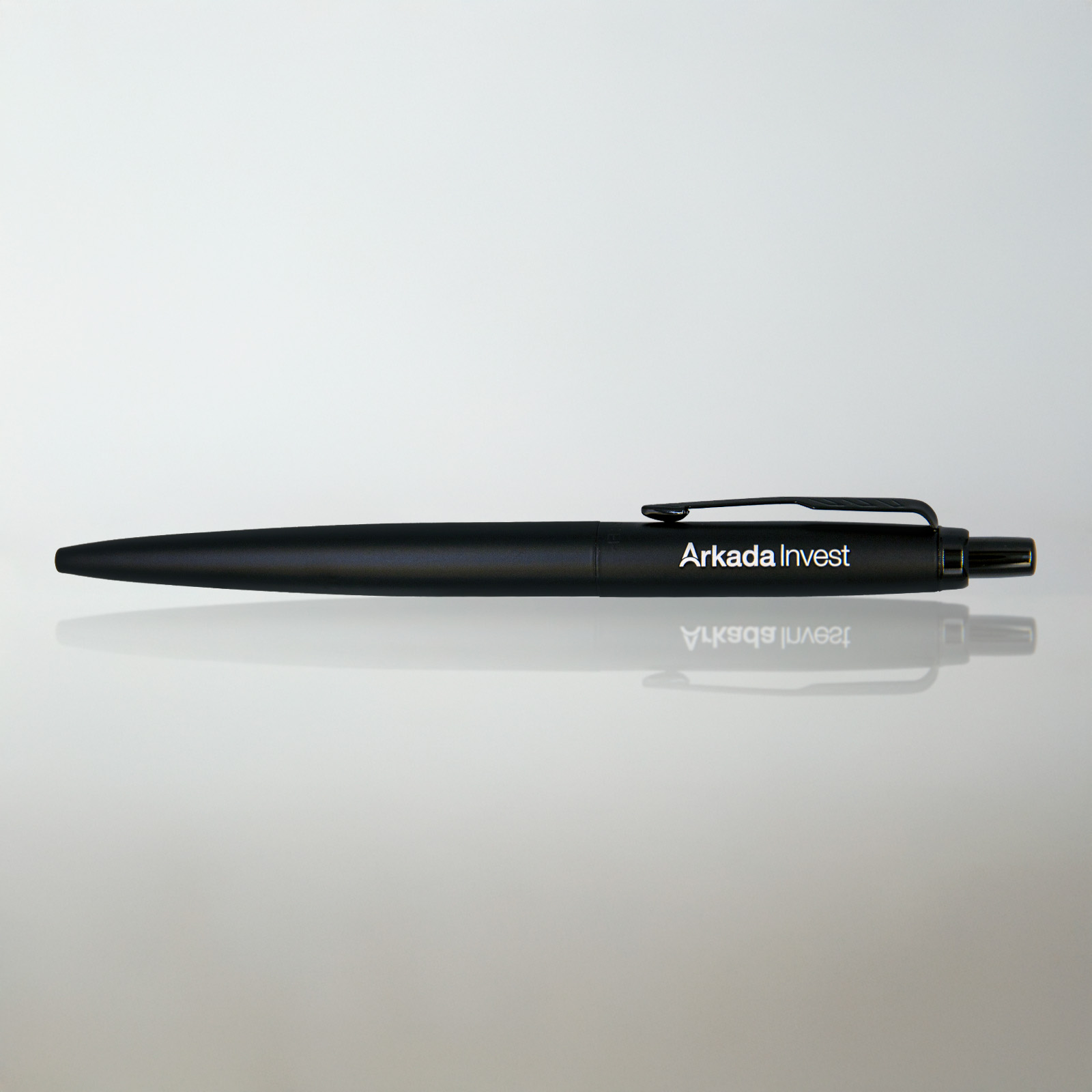 Długopis Parker Jotter XL Monochrome Black z grawerem „Arkada Invest”, na jasnym tle z subtelnym odbiciem i miękkim światłem.
