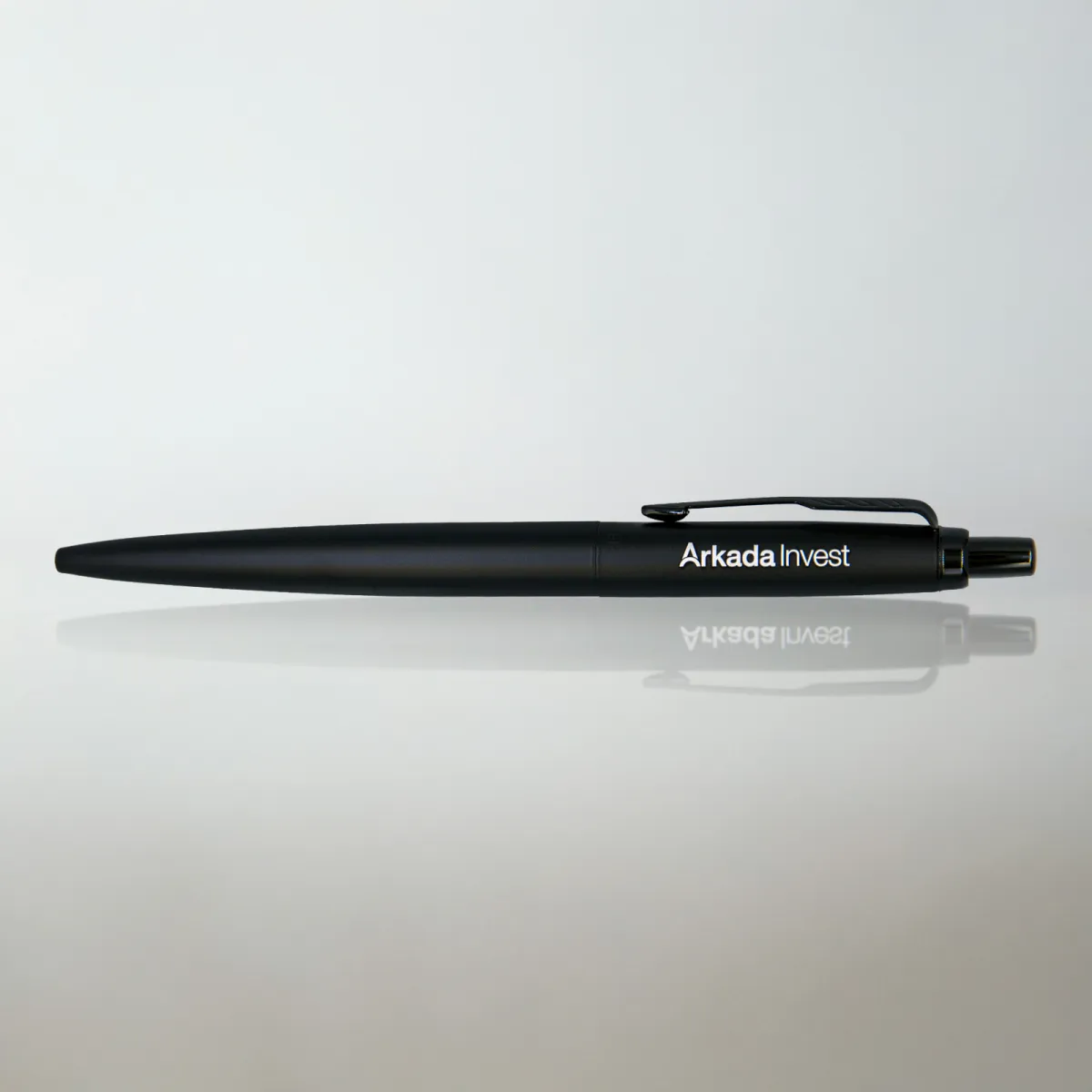Długopis Parker Jotter XL Monochrome Black z grawerem &bdquo;Arkada Invest&rdquo;, na jasnym tle z subtelnym odbiciem i miękkim światłem.