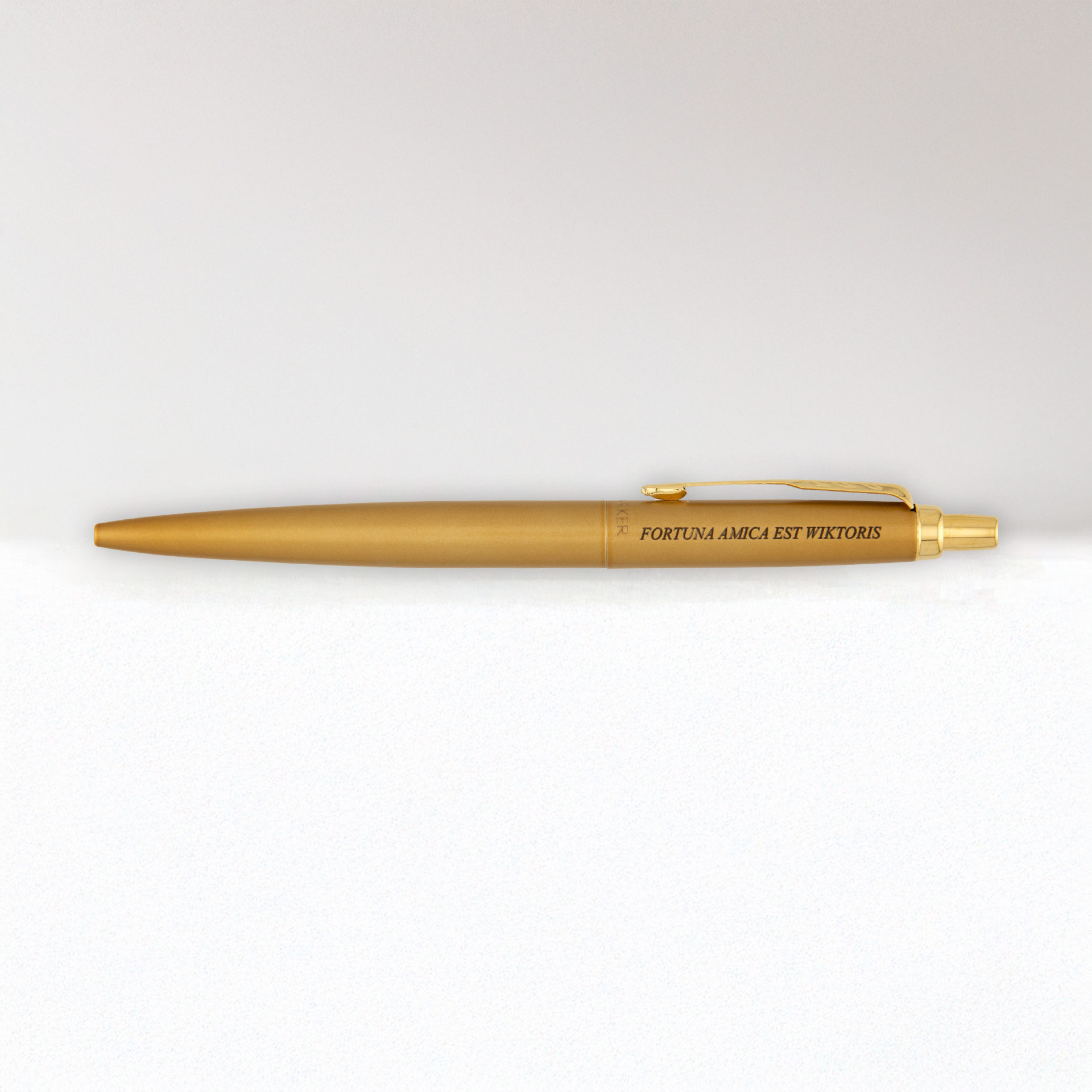 Złoty długopis z grawerem „FORTUNA AMICA EST WIKTORIS” na jasnym tle.