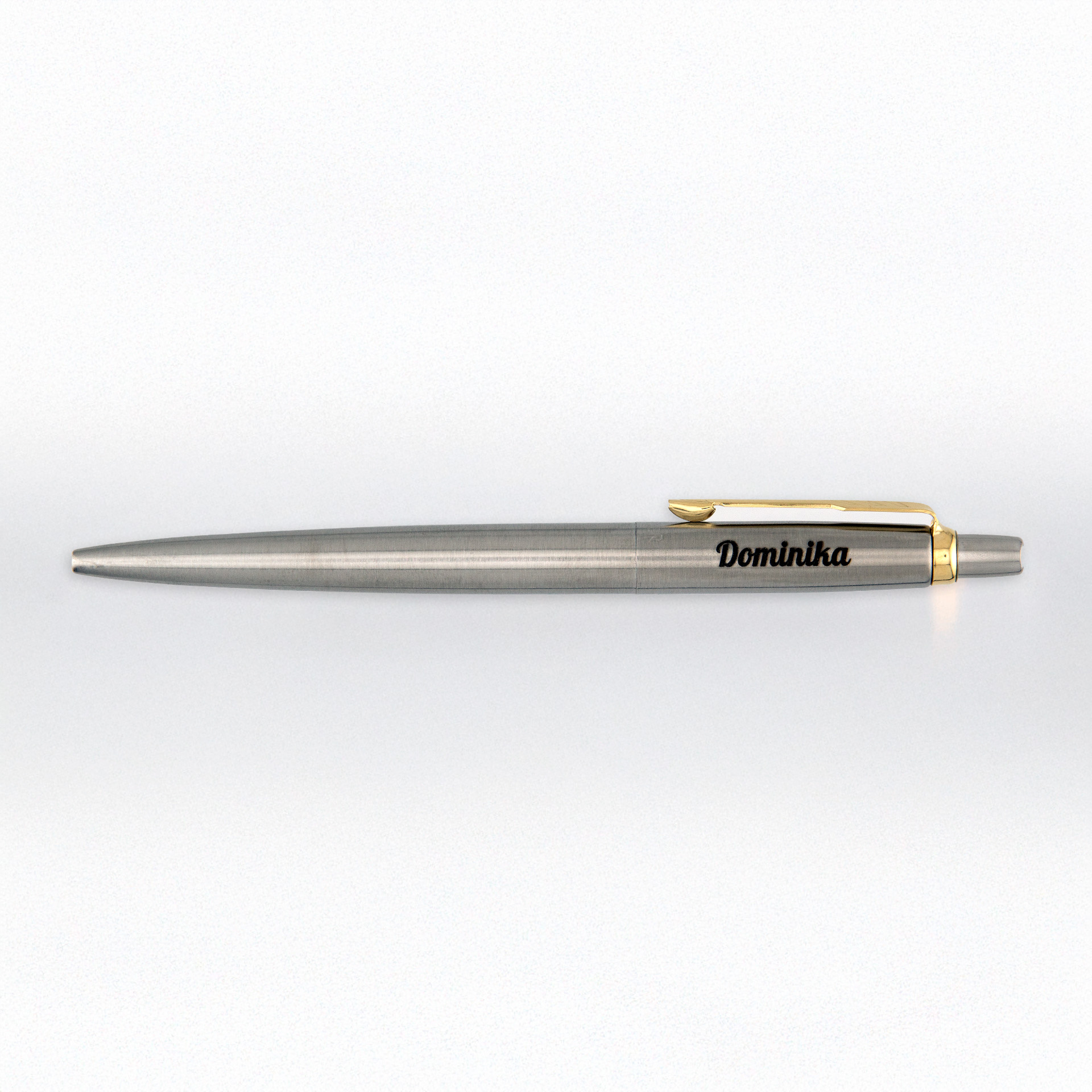 Stalowy Parker Jotter GT z grawerem „Dominika” leży na jasnym, minimalistycznym tle.