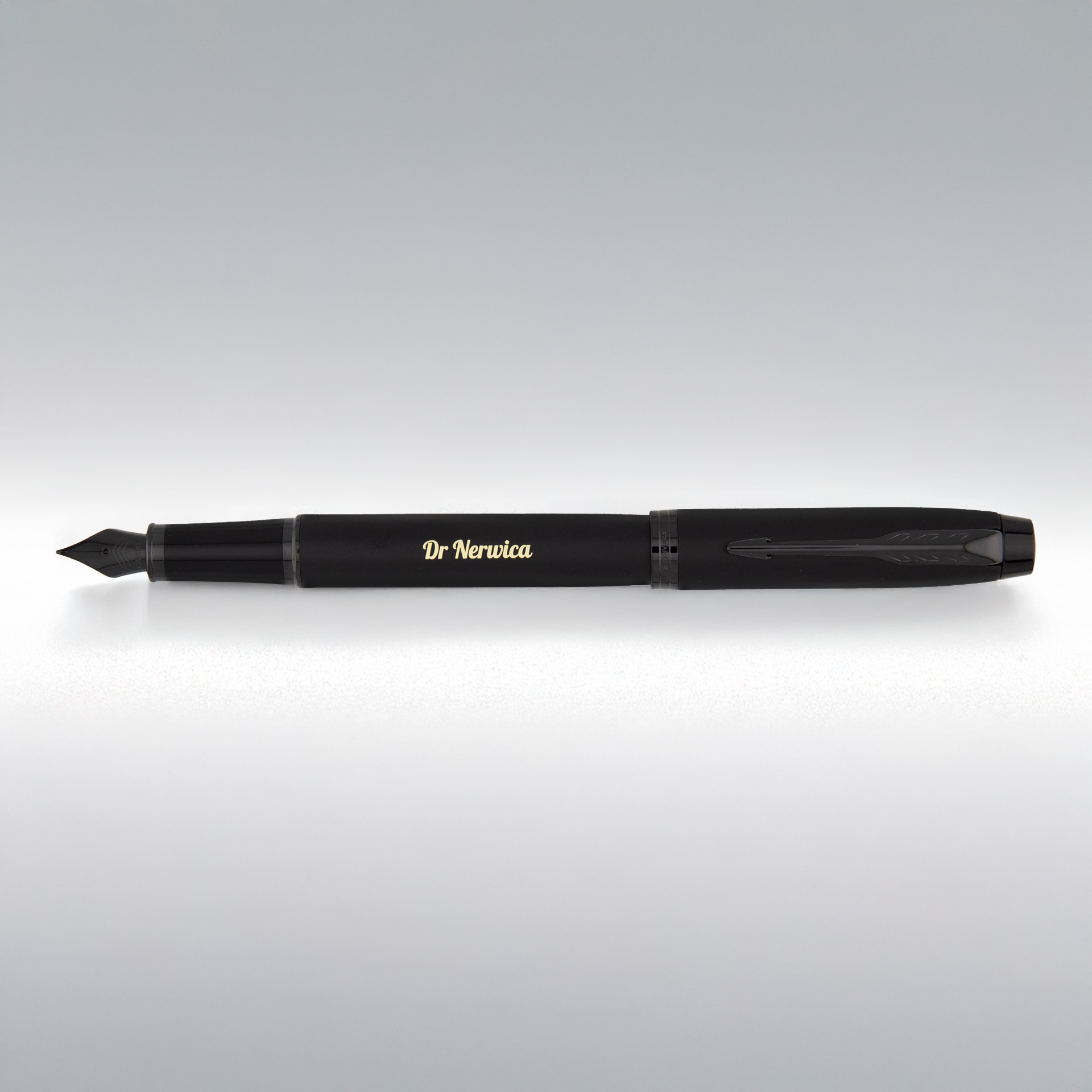Matowe czarne pióro z grawerem „Dr Nerwica” leży na jasnym tle, z widoczną czarną stalówką.