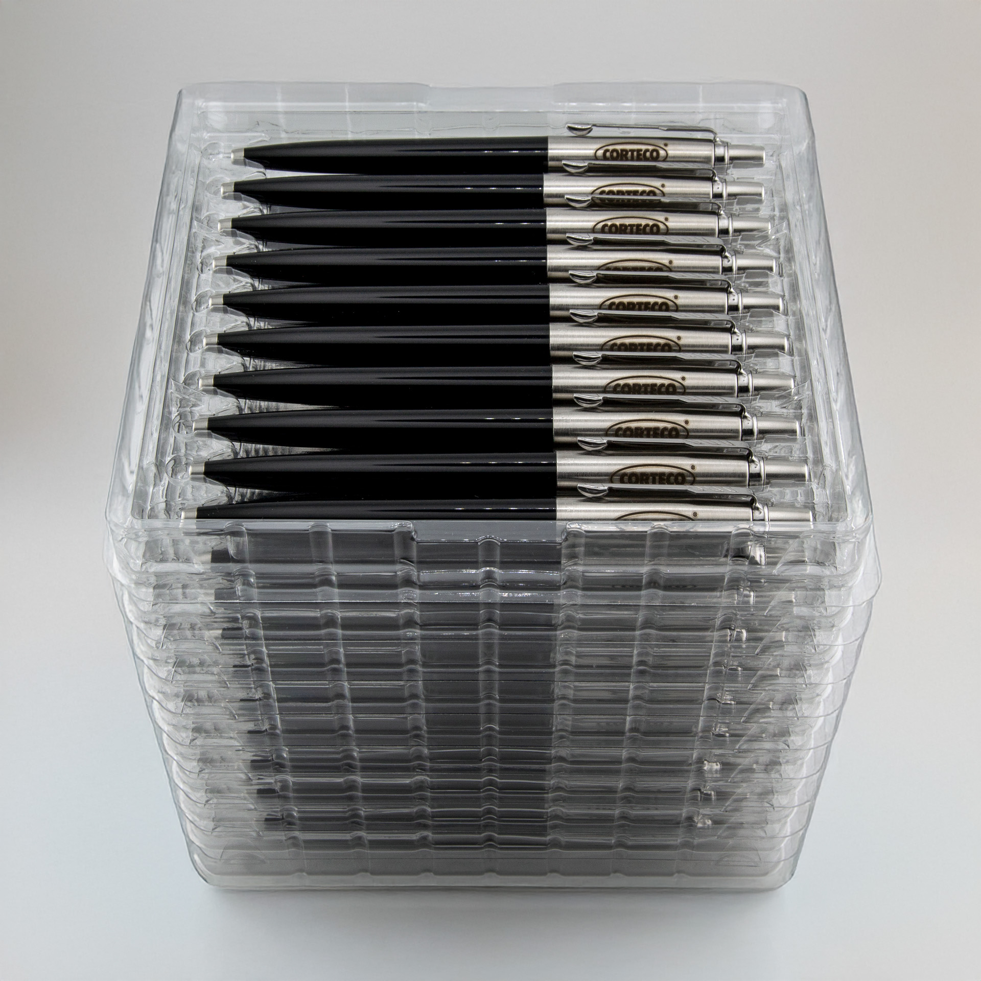 Zestaw czarnych długopisów z metalowym klipsem i logo CORTECO, ułożonych w przezroczystym plastikowym opakowaniu zbiorczym.