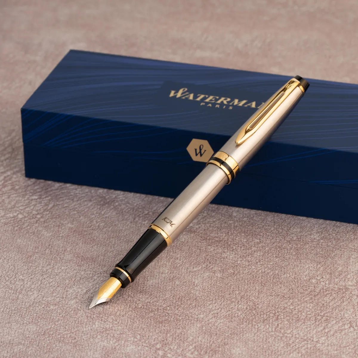 Pi&oacute;ro wieczne Waterman Expert stalowe GT z eleganckimi złotymi wykończeniami na tle granatowego pudełka Waterman Paris