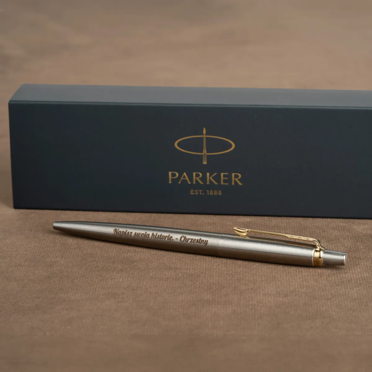 Długopis Parker Jotter Stalowy Matowy GT z personalizowanym grawerem &bdquo;Napisz swoją historię &ndash; Chrzestny&rdquo; na tle eleganckiego pudełka Parker