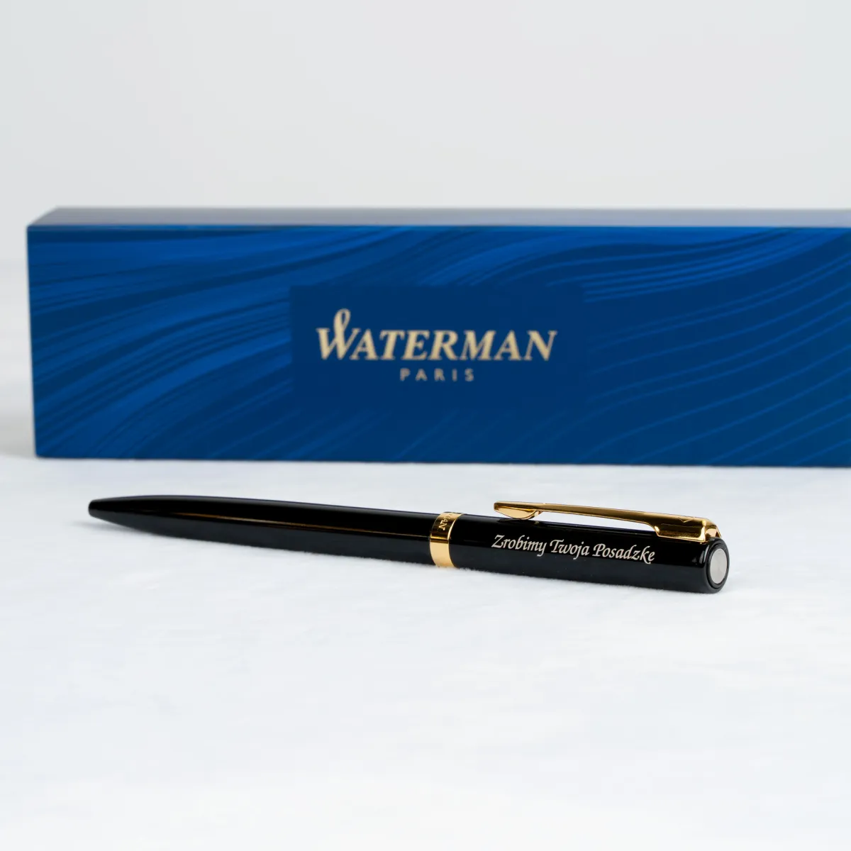 Długopis Waterman Impression czarny GT z personalizowanym grawerem „Zrobimy Twoją Posadzkę” na tle firmowego pudełka Waterman.