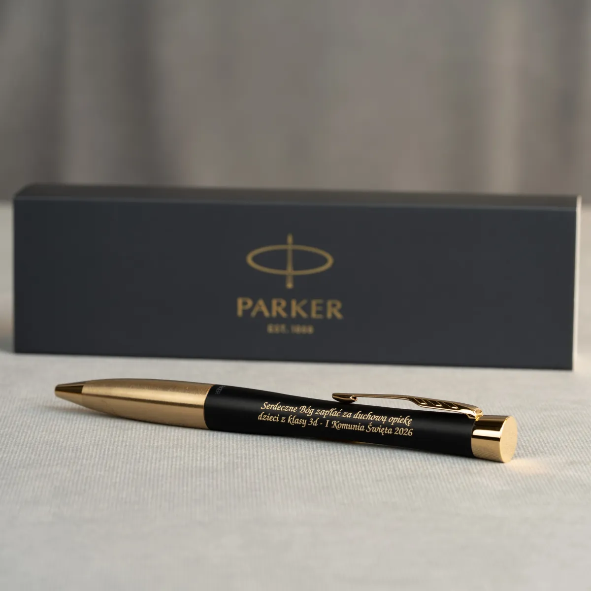 Długopis Parker Urban Czarny Matowy GT z grawerem podziękowania komunijnego na tle eleganckiego pudełka Parker.