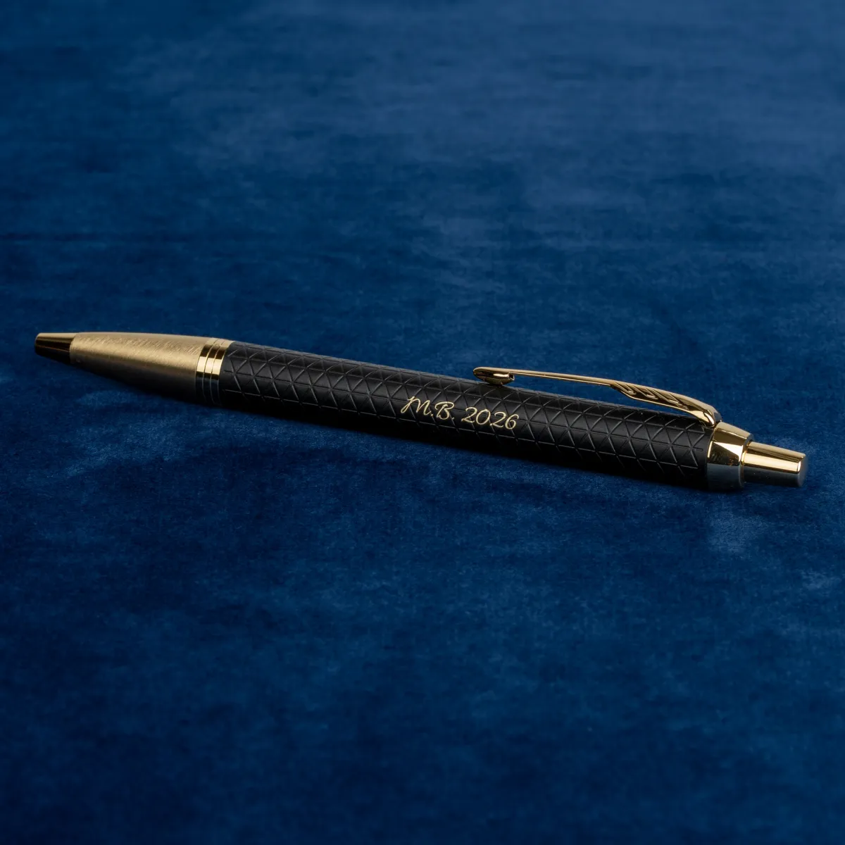 Długopis Parker IM Premium Czarny GT z personalizowanym grawerem &bdquo;M.B. 2026&rdquo; na eleganckim granatowym tle.